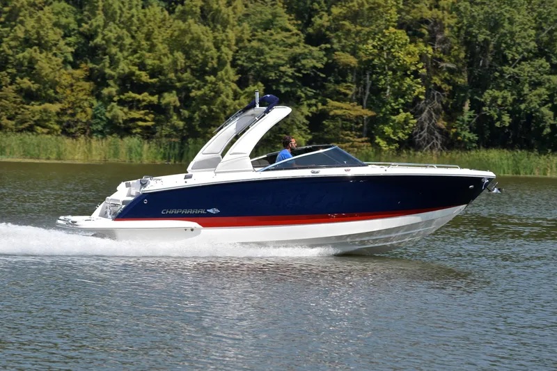 Slide: The Image of 2019 Chaparral 277 SSX boat cruising on a lake with lush green trees. - 3