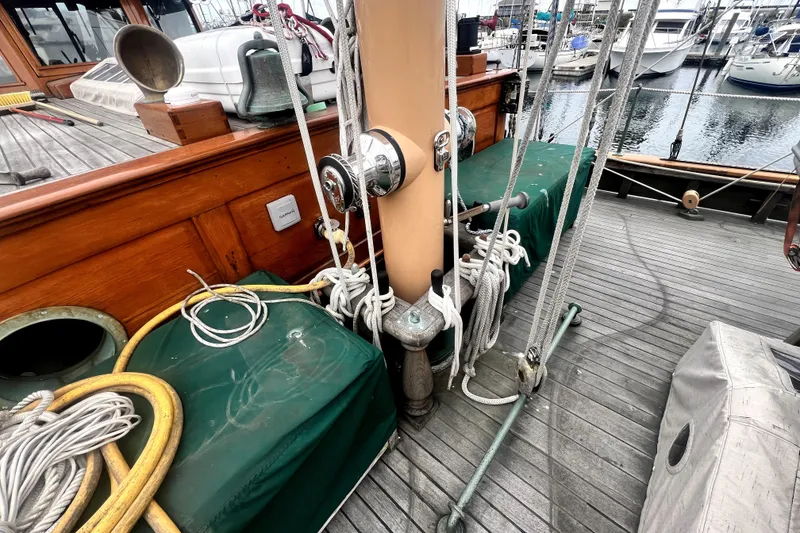 Slide: The Image of Deck of 1934 Pankey Schooner with ropes, winches, and covered equipment in a marina setting. - 15