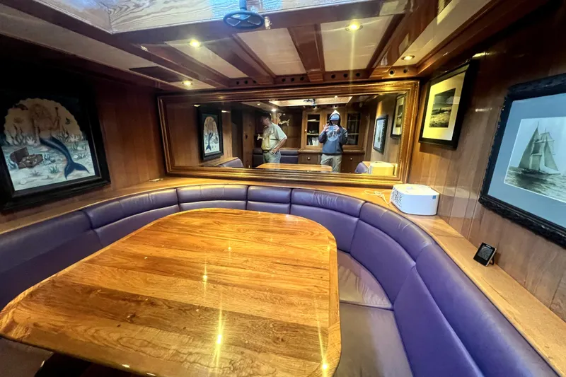 Slide: The Image of Interior of 1934 Pankey Schooner with wooden table, purple seating, and nautical artwork. - 39