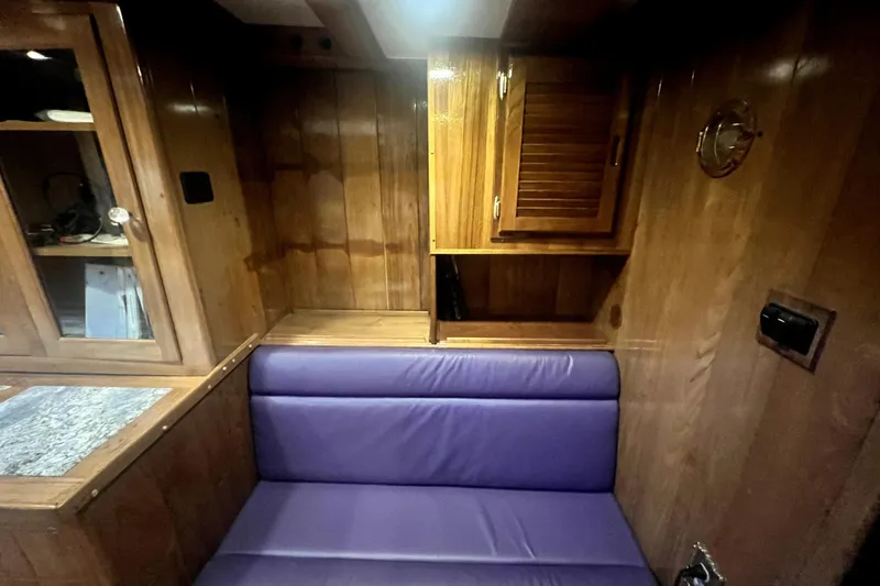 Slide: The Image of Interior of 1934 Pankey Schooner with wooden cabinets and purple cushioned seating. - 40