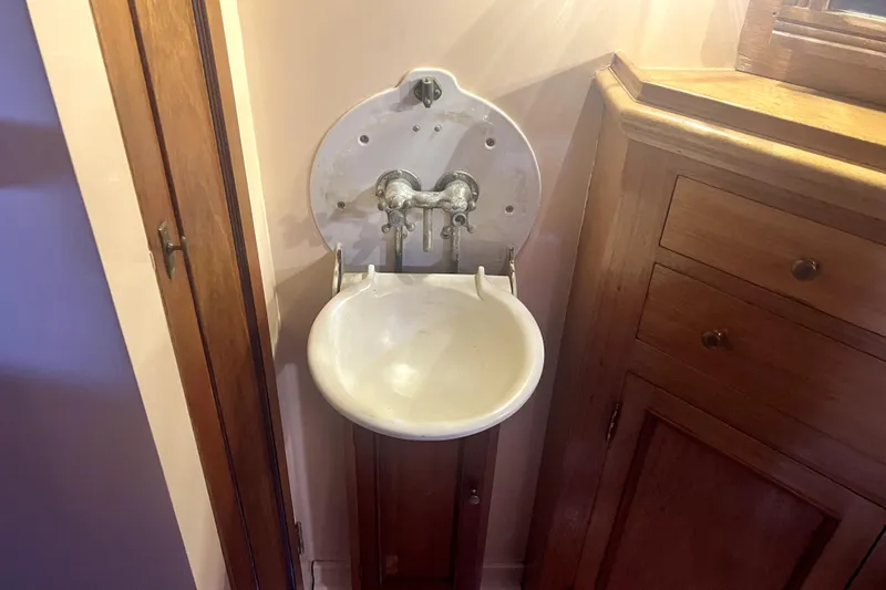 Slide: The Image of Vintage 1934 Pankey Schooner sink with wooden cabinetry in a cozy corner setting. - 44