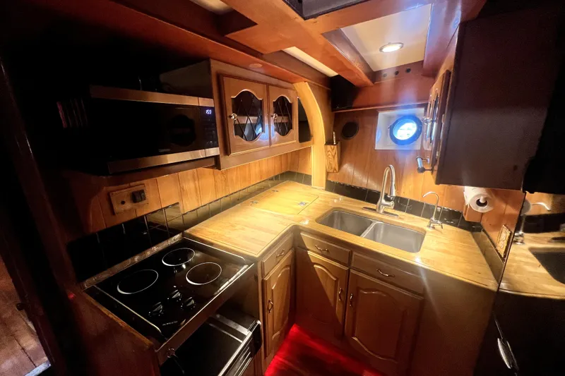 Slide: The Image of 1934 Pankey Schooner kitchen with wooden cabinetry, modern appliances, and porthole window. - 48