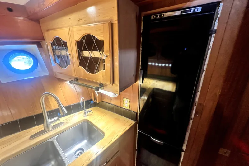 Slide: The Image of Wooden kitchen interior of 1934 Pankey Schooner with sink and porthole window. - 49