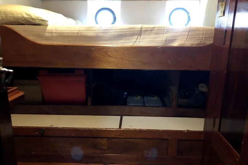 Slide: The Image of Wooden bunk bed with storage on a 1934 Pankey Schooner, featuring porthole windows. - 68