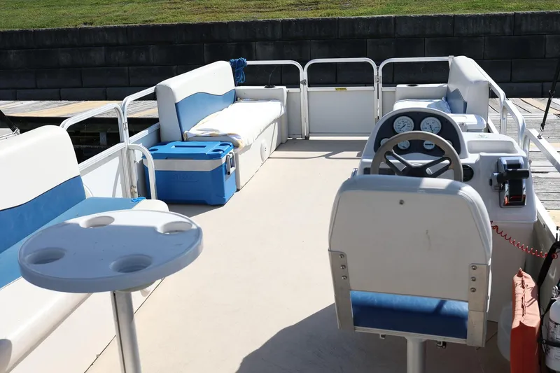 Slide: The Image of 2007 Sundancer Pontoons 24LX interior with blue seating, steering console, and table. - 8
