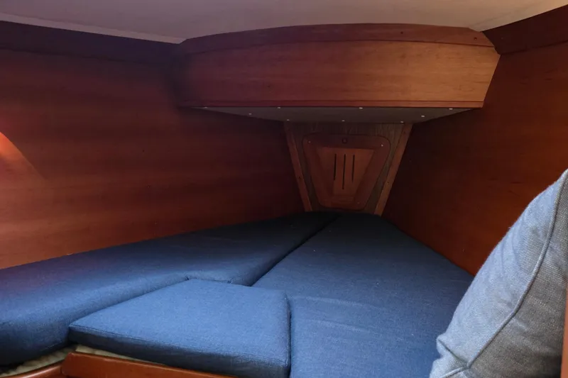 Slide: The Image of Interior cabin of a 1997 Freedom 35 sailboat with blue cushions and wooden paneling. - 14