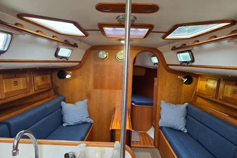 Slide: The Image of Cozy interior of a 1997 Freedom 35 sailboat with blue seating and wooden accents. - 4