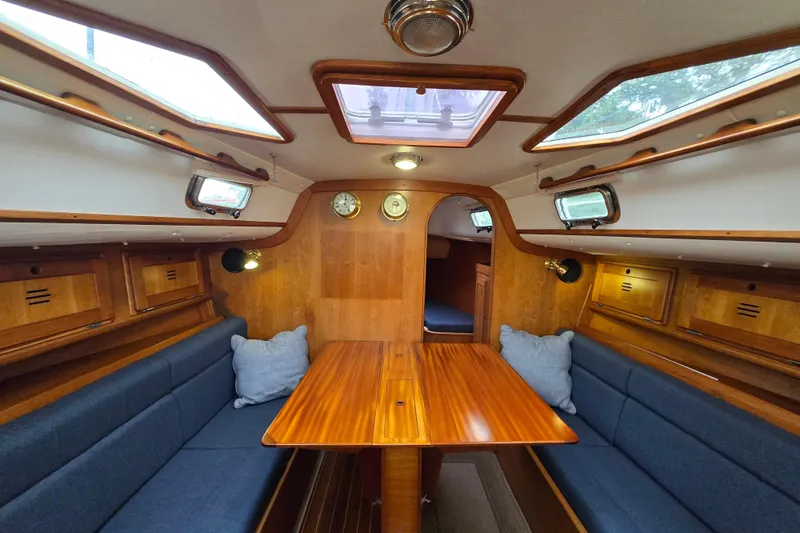 Slide: The Image of Cozy 1997 Freedom 35 sailboat interior with wooden finish and blue seating. - 5