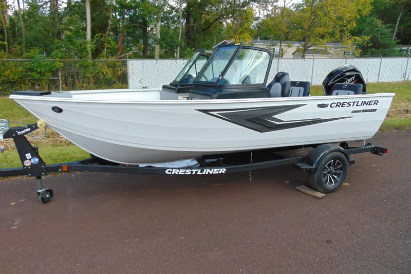 The Image of 2026 Crestliner 1650 Kodiak boat on trailer, parked outdoors with trees in background. - 1
