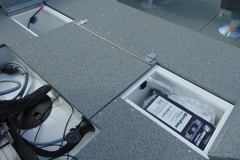 Slide: The Image of 2026 Crestliner 1650 Kodiak boat storage compartments with gray carpeted deck. - 14