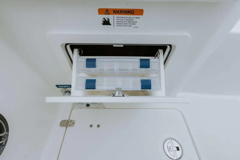 Slide: The Image of 2026 World Cat 235TE boat storage compartment with warning label and secure latch. - 46