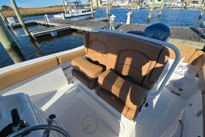 Slide: The Image of 2019 Sea Hunt Ultra 255 SE boat interior with tan seating at a marina. - 18