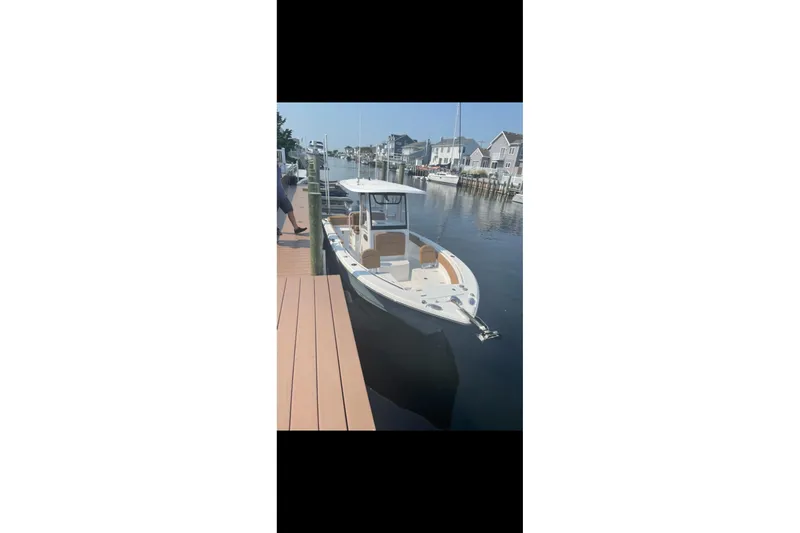 Slide: The Image of 2019 Sea Hunt Ultra 255 SE boat docked in a serene waterfront setting. - 4