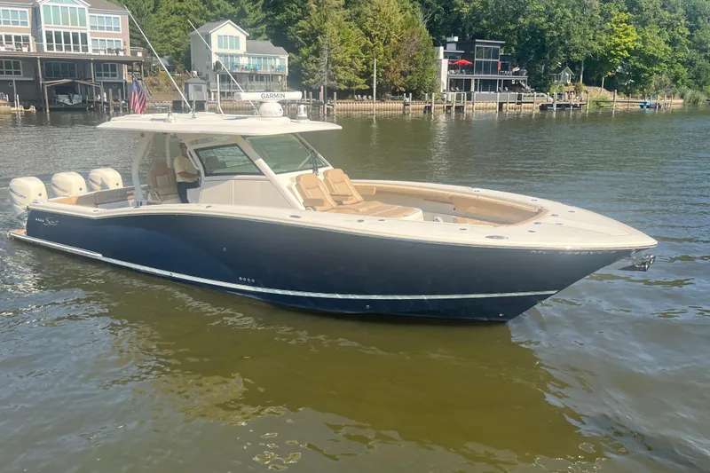 Slide: The Image of 2020 Scout 380 LXF boat on a calm lake near waterfront homes. - 1