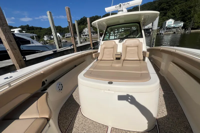 Slide: The Image of 2020 Scout 380 LXF boat interior with tan seating, docked by waterfront homes. - 13