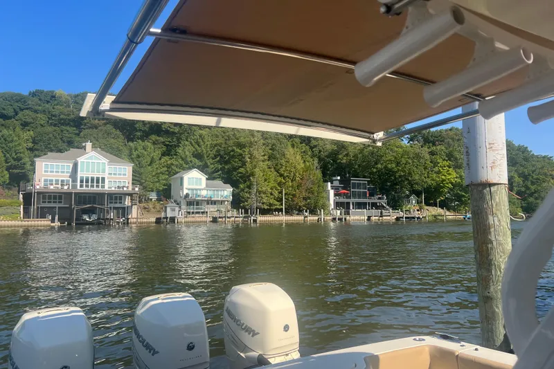 Slide: The Image of 2020 Scout 380 LXF boat on a serene lake with waterfront homes in the background. - 17