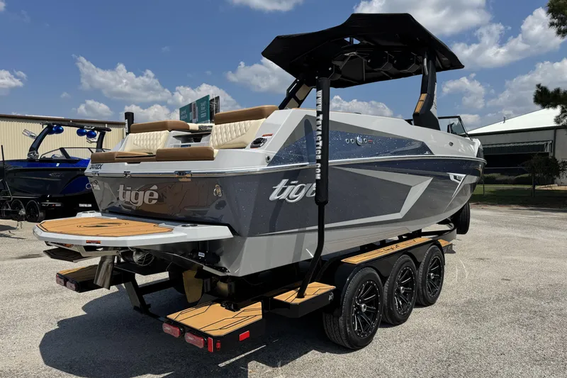 Slide: The Image of 2026 Tigé 24RZX boat on trailer, sleek design, parked outdoors under blue sky. - 4