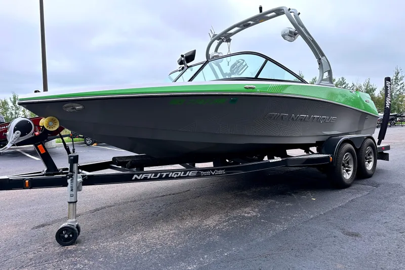 Slide: The Image of 2012 Nautique Sport Nautique 200 boat on trailer, green and gray design, parked outdoors. - 2