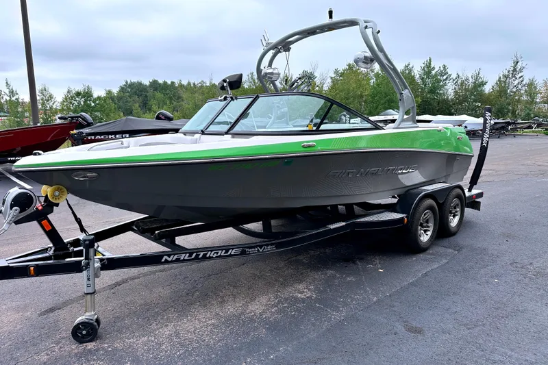 Slide: The Image of 2012 Nautique Sport Nautique 200 boat on trailer, green and gray design, parked outdoors. - 3