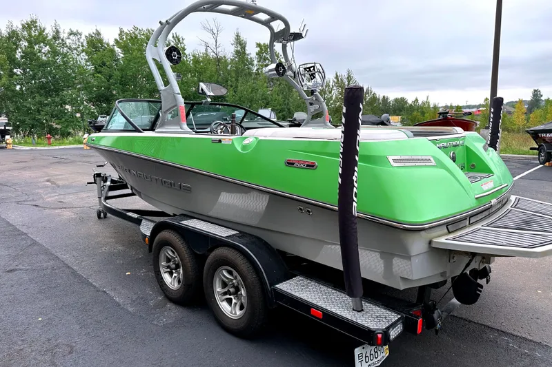 Slide: The Image of 2012 Nautique Sport Nautique 200 boat in vibrant green on a trailer, parked outdoors. - 7