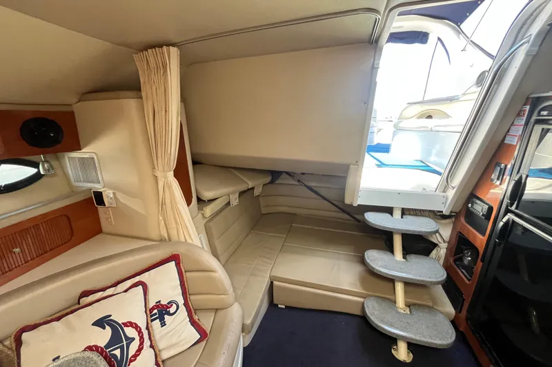 Slide: The Image of 2005 Larson-Cabrio 370 interior with beige seating, nautical pillows, and compact stairs. - 20