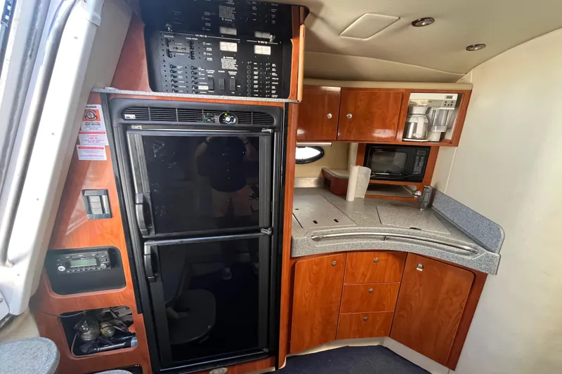 Slide: The Image of 2005 Larson-Cabrio 370 yacht interior kitchen with wood cabinets, fridge, and appliances. - 23