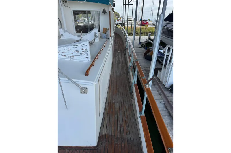 Slide: The Image of 1978 Grand Banks Classic yacht deck with wooden railings and white cabin exterior. - 12