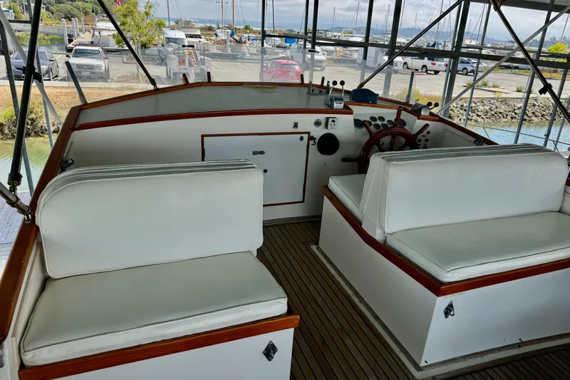 Slide: The Image of 1978 Grand Banks Classic boat interior with white seating and wooden accents at a marina. - 19