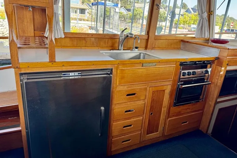 Slide: The Image of 1978 Grand Banks Classic yacht kitchen with wooden cabinetry, stainless steel appliances, and a sink. - 24