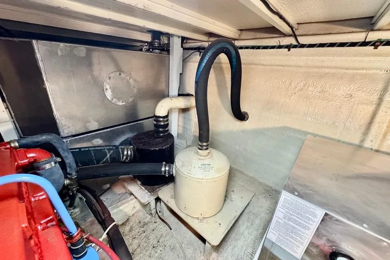 Slide: The Image of Engine room of a 1978 Grand Banks Classic boat, showing hoses and machinery. - 38