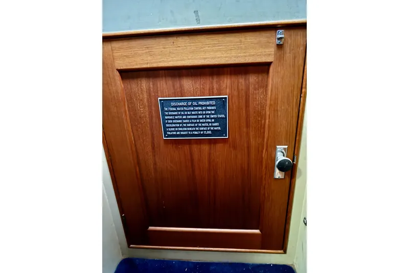 Slide: The Image of Wooden door with oil discharge warning plaque on 1978 Grand Banks Classic boat. - 72