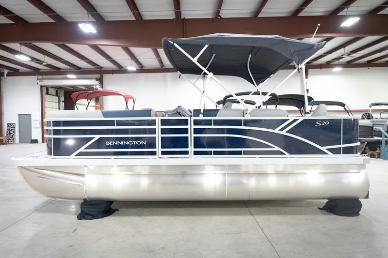 Slide: The Image of 2026 Bennington 20 SFC pontoon boat in showroom, featuring sleek design and canopy. - 11