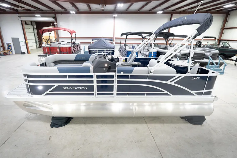 Slide: The Image of 2026 Bennington 20 SFC pontoon boat in indoor showroom, featuring sleek design and canopy. - 2