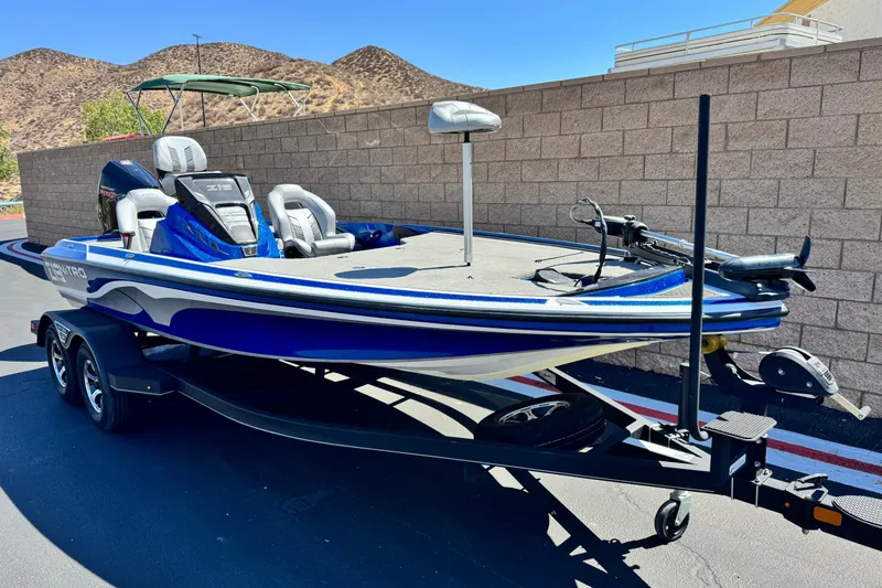Slide: The Image of 2022 Nitro Z19 boat on trailer, blue and white, parked by a brick wall. - 1