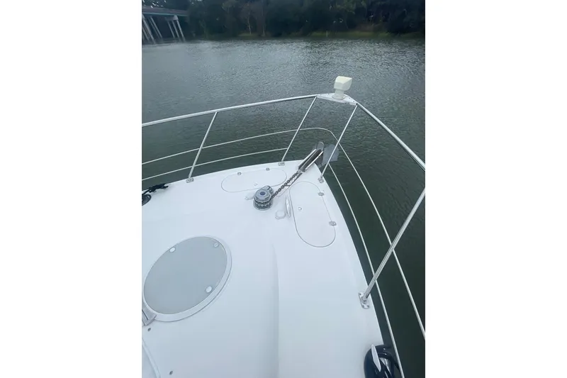 Slide: The Image of 2004 Carver 570 Voyager Pilothouse yacht on a calm river, surrounded by trees. - 74