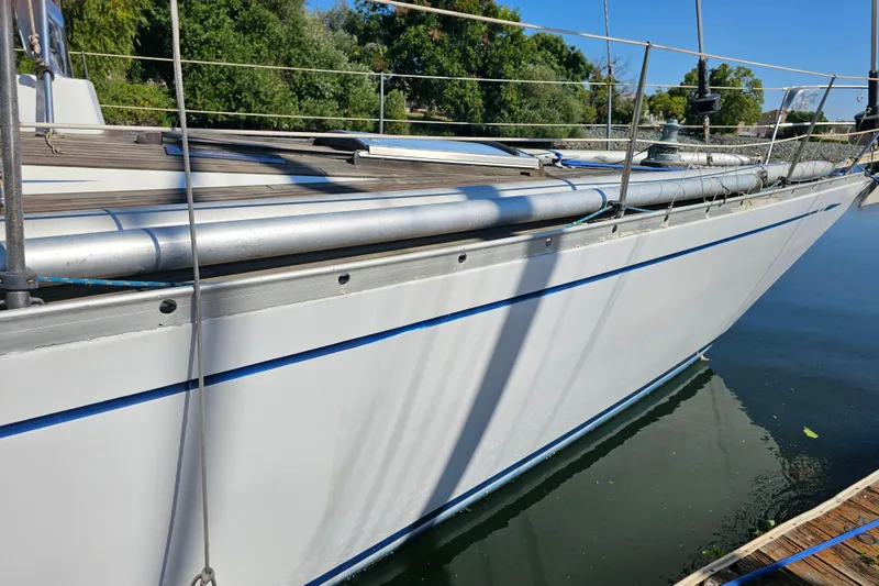 Slide: The Image of 1980 Nautor Swan 47 sailboat with wooden deck and blue canopy, docked on calm water. - 6