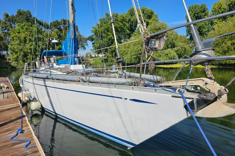 Slide: The Image of 1980 Nautor Swan 47 sailboat docked on a serene river with lush greenery. - 7