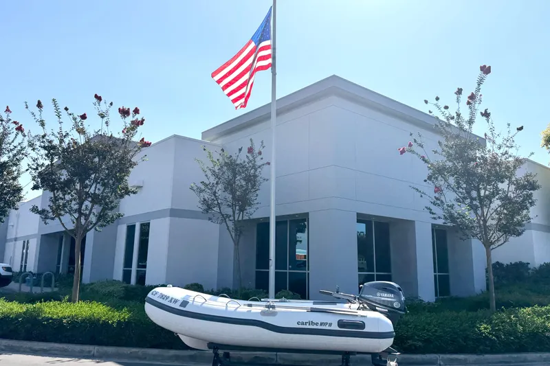 Slide: The Image of Inflatable Caribe MPV 10 boat, 2025 model, displayed outside a building with American flag. - 11