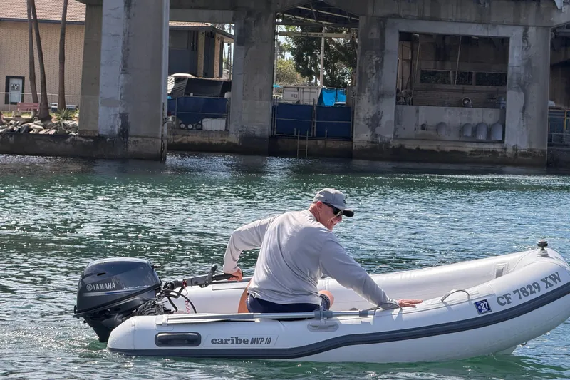 Slide: The Image of Man navigating a Caribe MPV 10 inflatable boat under a bridge, 2025 model. - 44