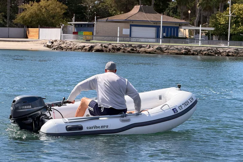 Slide: The Image of Man operating Caribe MPV 10 inflatable boat with Yamaha motor on calm water. - 45