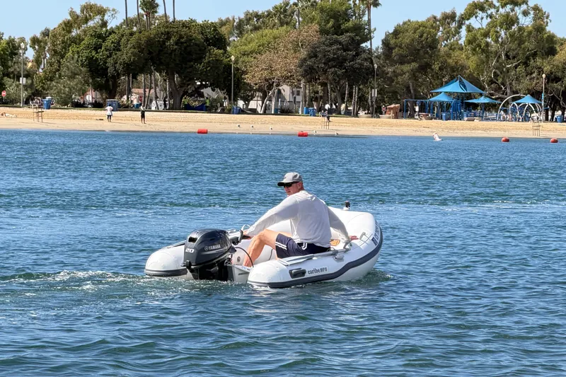 Slide: The Image of Man operating Caribe MPV 10 inflatable boat on a sunny day near a beach. - 47