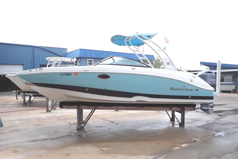 Slide: The Image of 2019 NauticStar 243DC Sport Deck boat on display at a marina. - 1