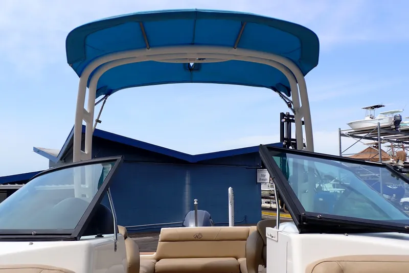 Slide: The Image of 2019 NauticStar 243DC Sport Deck boat with blue canopy and open seating area. - 17