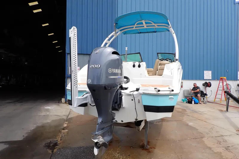 Slide: The Image of 2019 NauticStar 243DC Sport Deck boat with Yamaha 200 engine, docked near a blue building. - 2