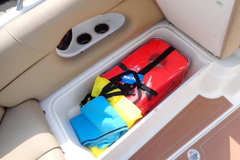 Slide: The Image of 2019 NauticStar 243DC Sport Deck storage compartment with life jackets and gear. - 36