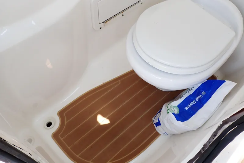 Slide: The Image of 2019 NauticStar 243DC Sport Deck boat bathroom with toilet and marine supplies. - 49