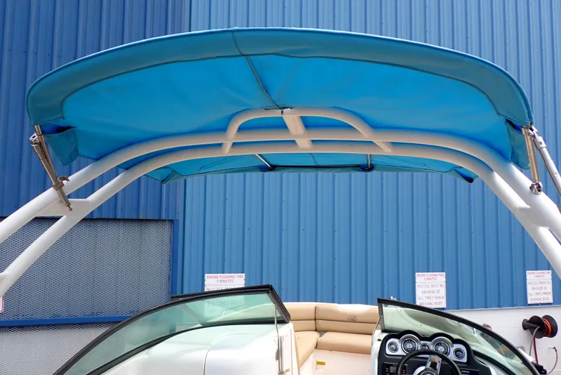 Slide: The Image of 2019 NauticStar 243DC Sport Deck boat with blue canopy and dashboard view. - 5