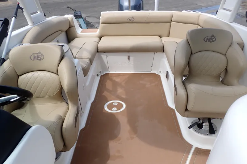 Slide: The Image of 2019 NauticStar 243DC Sport Deck interior with beige seating and spacious layout. - 8