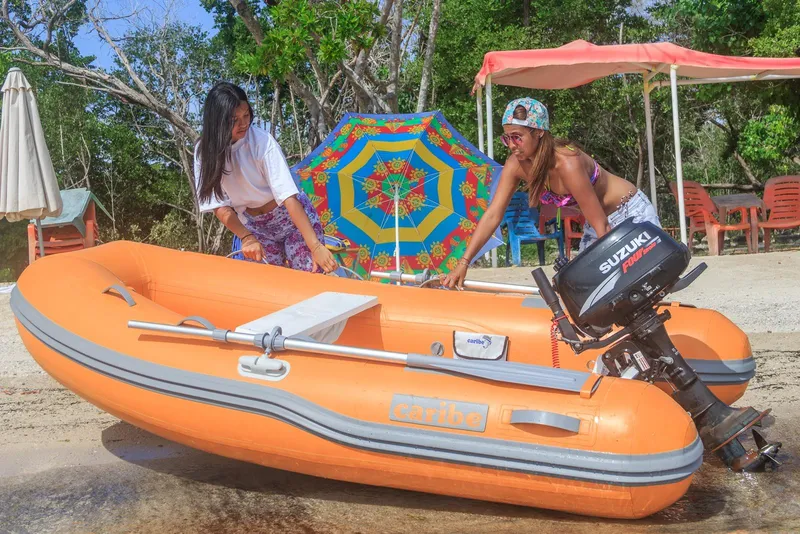 Slide: The Image of Two women with an orange Caribe L9 inflatable boat on a sunny beach. - 4
