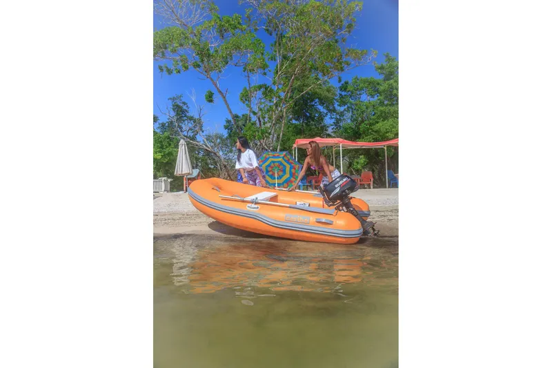 Slide: The Image of Two people with an orange Caribe L9 inflatable boat on a sunny beach. - 5